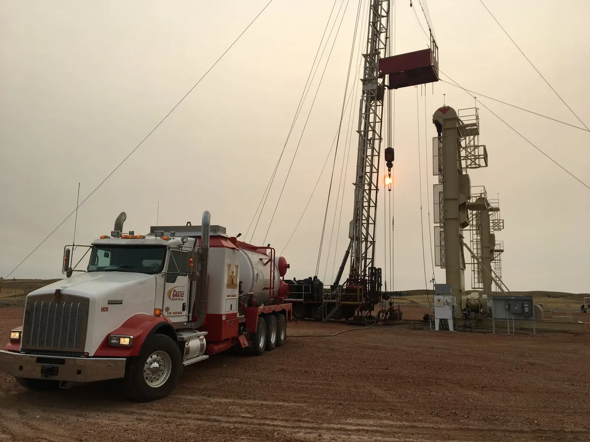 A Castle Oilfield Services truck on location beside a workover rig