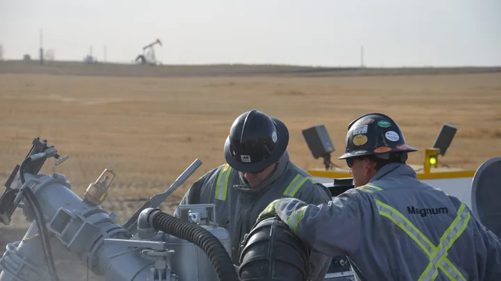 Two Magnum hands working on cementing equipment