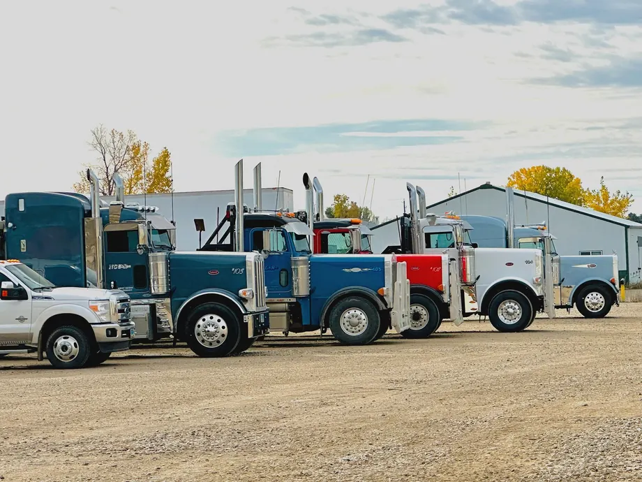 North Country Construction & Rentals trucks lined up outside their shop: blue, red and white Peterbilts and a pickup